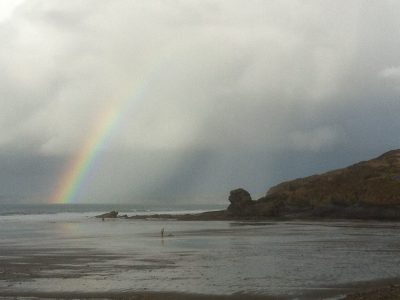 A rainbow over a rainy view of Lion Rock on Broad Haven beach
